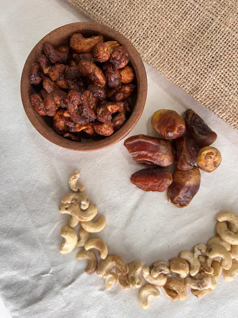 Bowl de castañas de cajú horneadas con pasta de dátil, rodeado de dátiles y castañas