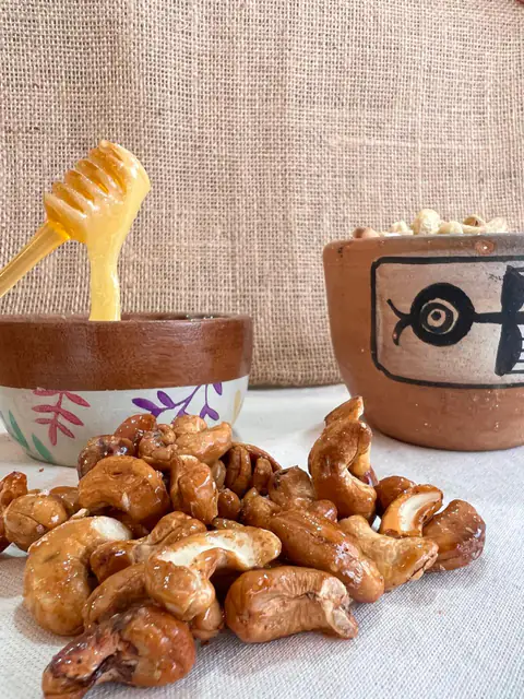 Castañas de cajú horneadas con miel junto a un bowl con miel y su cuchara