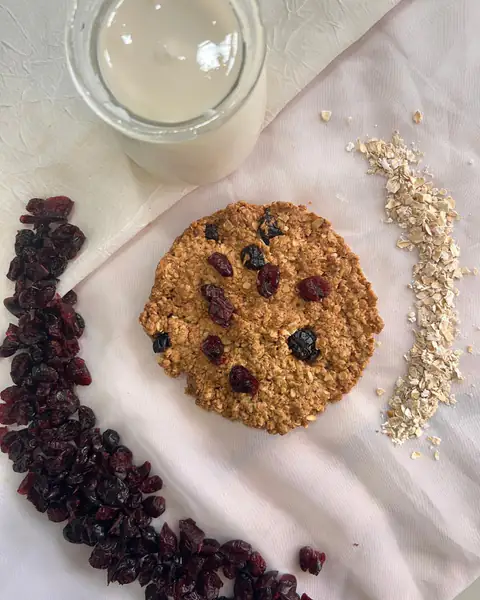 Galletita de avena con arándanos rojos, rodeada de arándanos y copos de avena