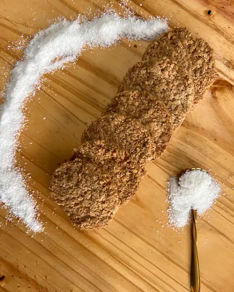 Galletitas de coco apiladas sobre madera junto a coco rallado