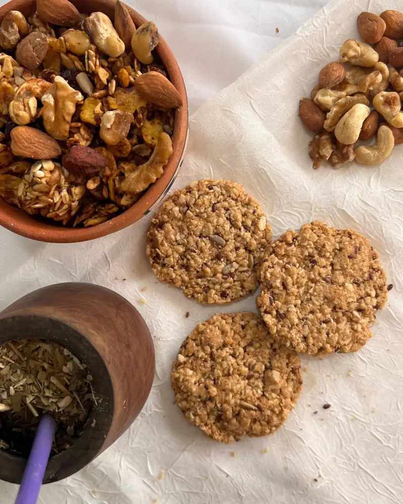 Galletitas de avena junto a un bowl de frutos secos y un mate