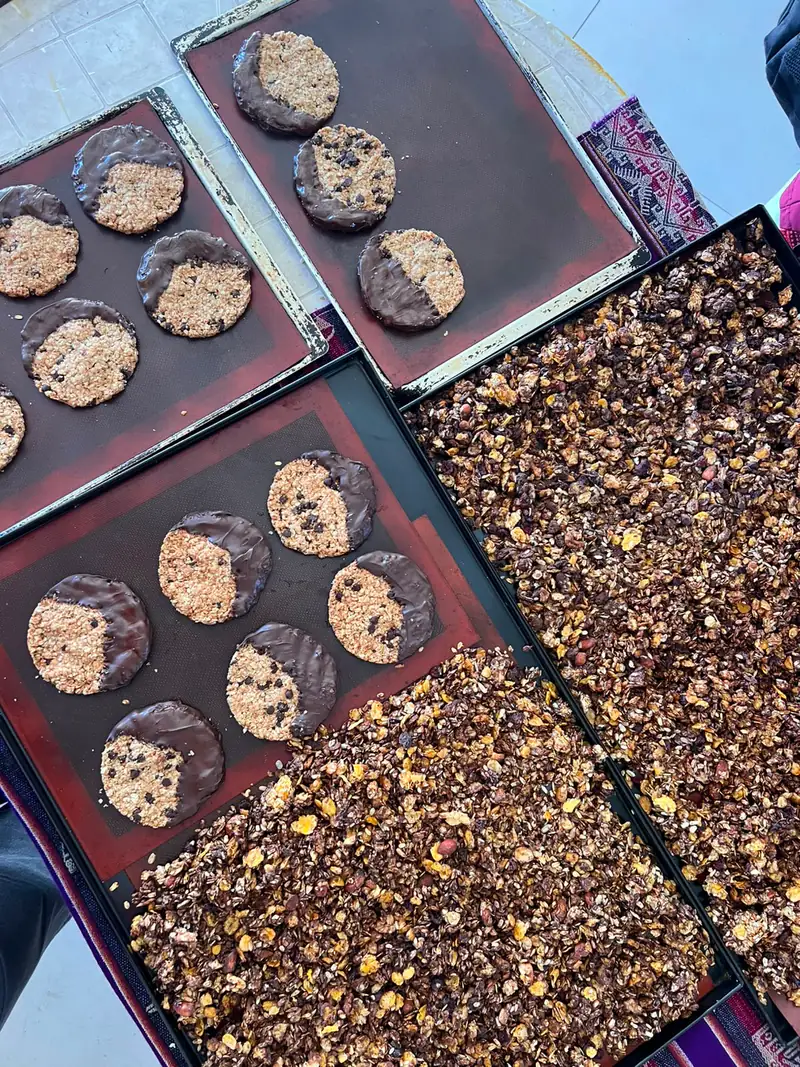 Bandejas con galletitas bañadas en chocolate y granola con chocolate en plena producción